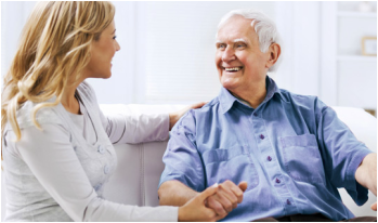 Caregiver holding an older man’s hand at home
