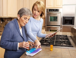 Caregiver helping an older woman with her medications
